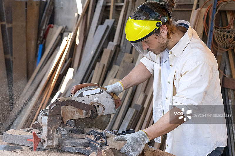 木匠在车间工作，正在锯木板。图片素材