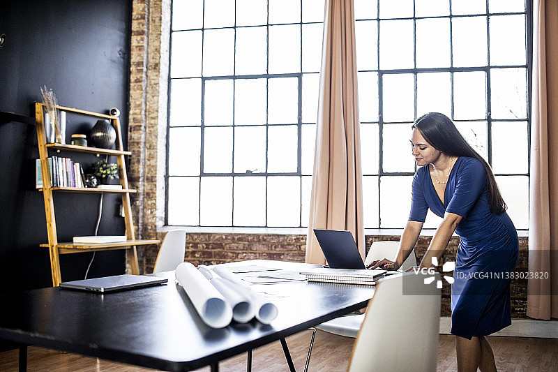 在现代办公空间使用笔记本电脑的年轻职业女性图片素材