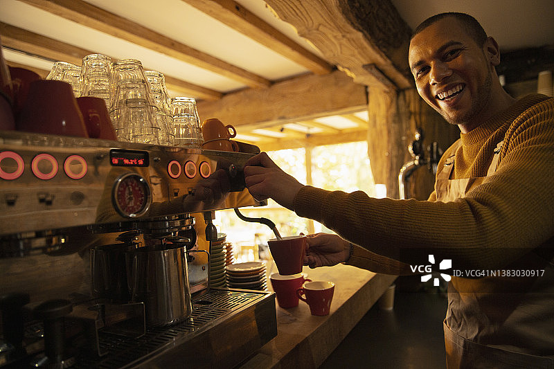 快乐的男咖啡师在咖啡馆用咖啡机准备咖啡图片素材
