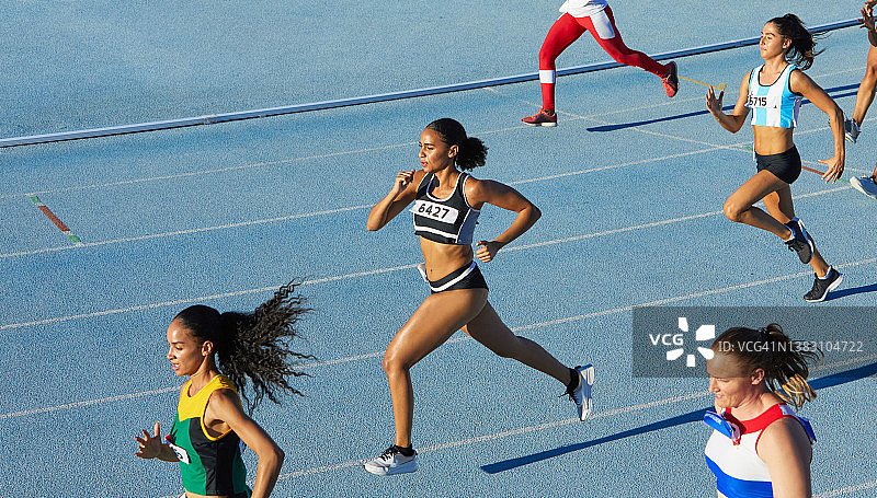 在蓝色跑道上参加田径比赛的女运动员图片素材