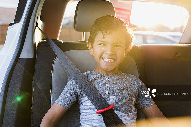 男孩系好汽车增高座椅安全带，对着镜头微笑图片素材