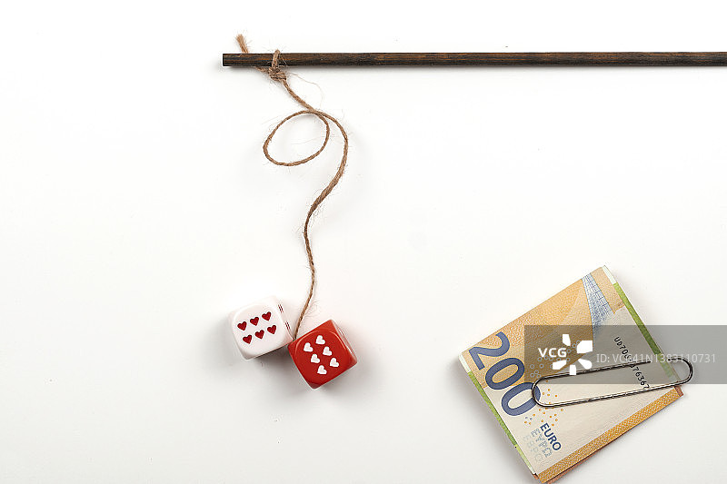 棍子上的两个摇晃的骰子和欧元纸币，象征着在光线背景下的赌博成瘾概念图片素材