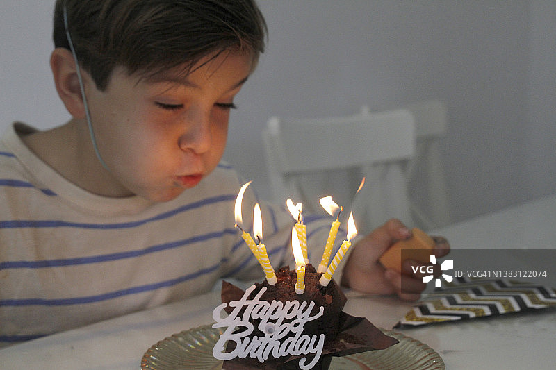 男孩吹灭生日蛋糕上的蜡烛图片素材