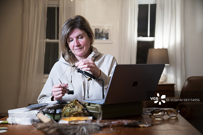 一个女人学习如何绑飞蝇钓鱼的鱼钩图片素材