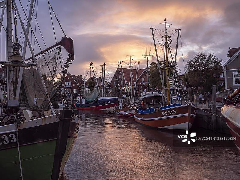 日落时分，诺伊哈林格斯iel港口的捕蟹船，德国下萨克森州图片素材