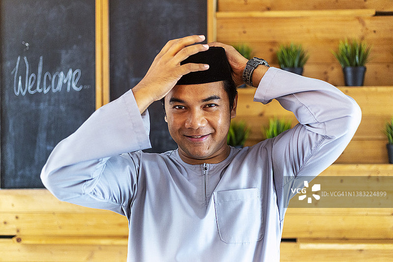 穆斯林男子在家调整宋谷帽和马来传统服装图片素材