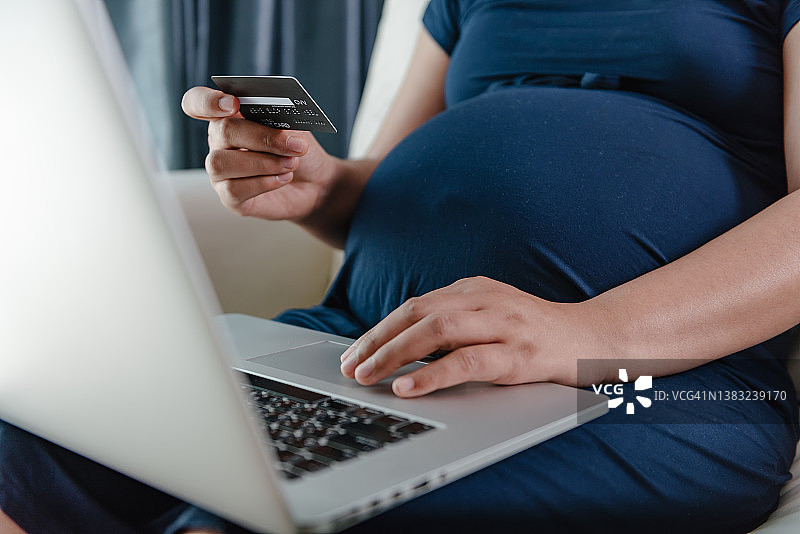 孕妇在家使用笔记本电脑进行网上购物图片素材