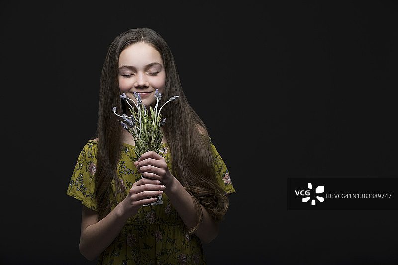 手捧葡萄风信子的微笑女孩，影棚肖像照图片素材