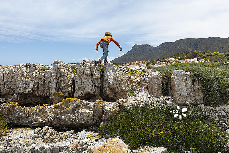 南非赫曼努斯男孩在桑德拜海滩探索岩石图片素材