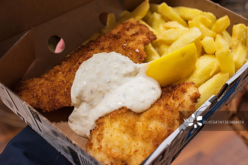 新鲜出炉的炸鱼薯条外卖，顶部有酱汁图片素材