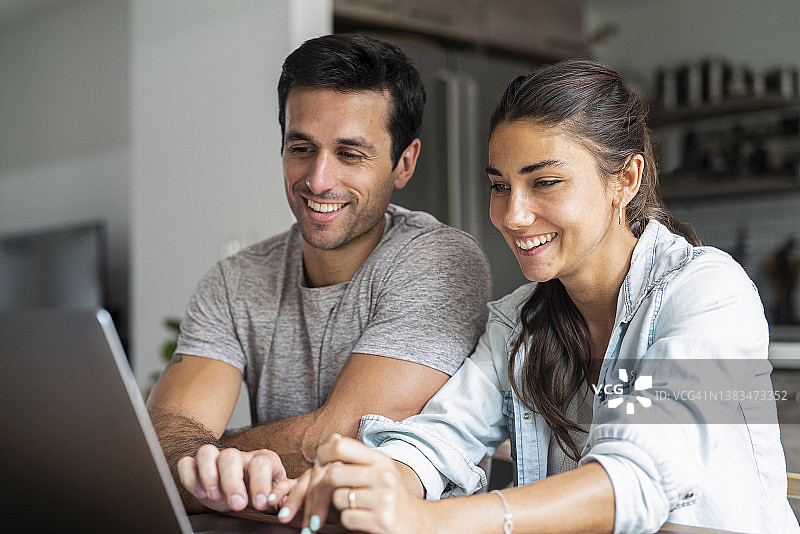 快乐的西班牙裔夫妇在笔记本电脑上进行网上购物图片素材