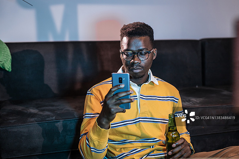 看电视并在手机上看新闻的年轻男人图片素材