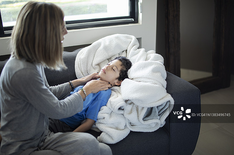 母亲在沙发上检查孩子的喉咙图片素材