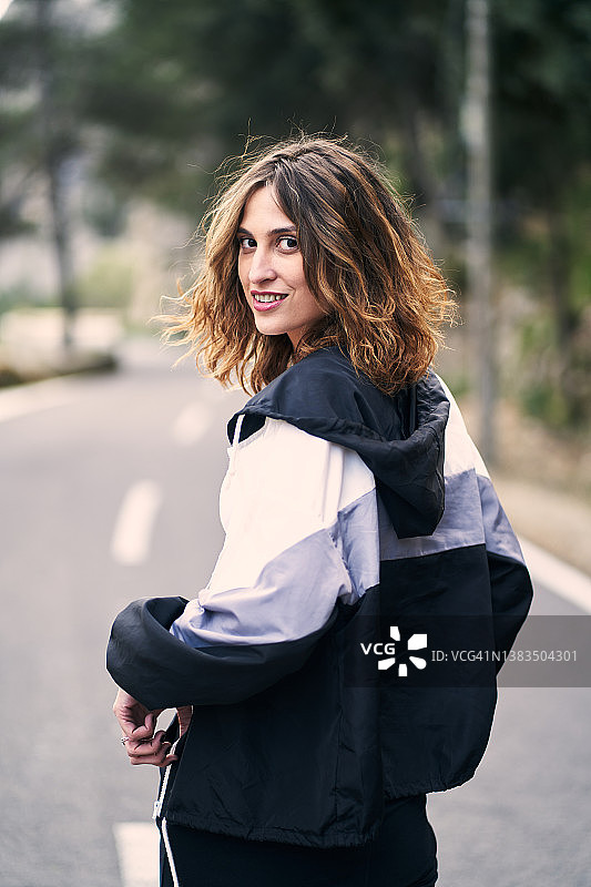 穿运动夹克站在路上的微笑女人图片素材