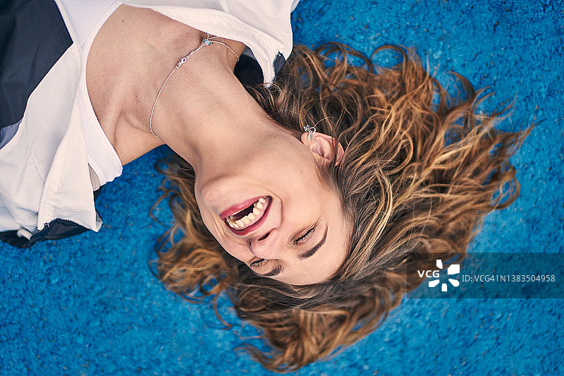 快乐的女人躺在地上灿烂地笑着图片素材