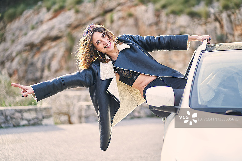 在高地从车里探出头的快乐旅行女性图片素材
