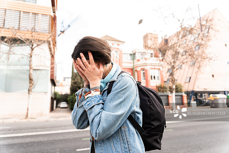 白天走在街上，用手捂住脸的悲伤女人图片素材