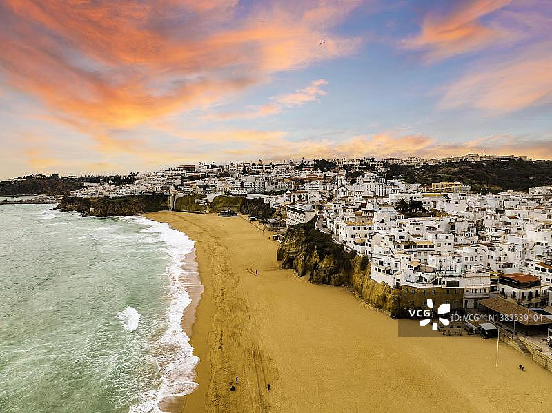 阿尔布费拉大西洋沿岸粉刷建筑的航拍，日落时分的城镇景观，阿尔加维，葡萄牙图片素材