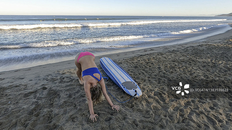 冲浪前在沙滩上伸展身体的女人图片素材