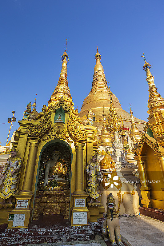 阳光明媚的一天，缅甸仰光金色的大金塔前的小型宝塔和雕像图片素材