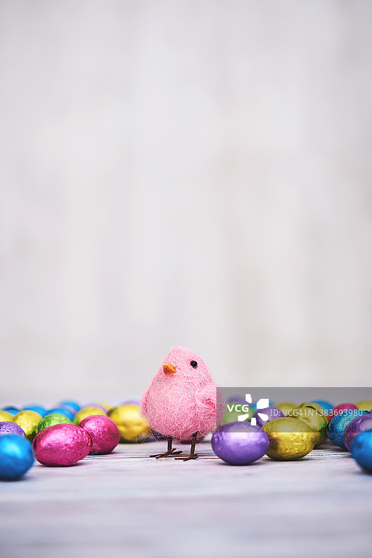 乡村木桌上，可爱的粉色复活节小鸡与锡箔纸包裹的复活节彩蛋图片素材