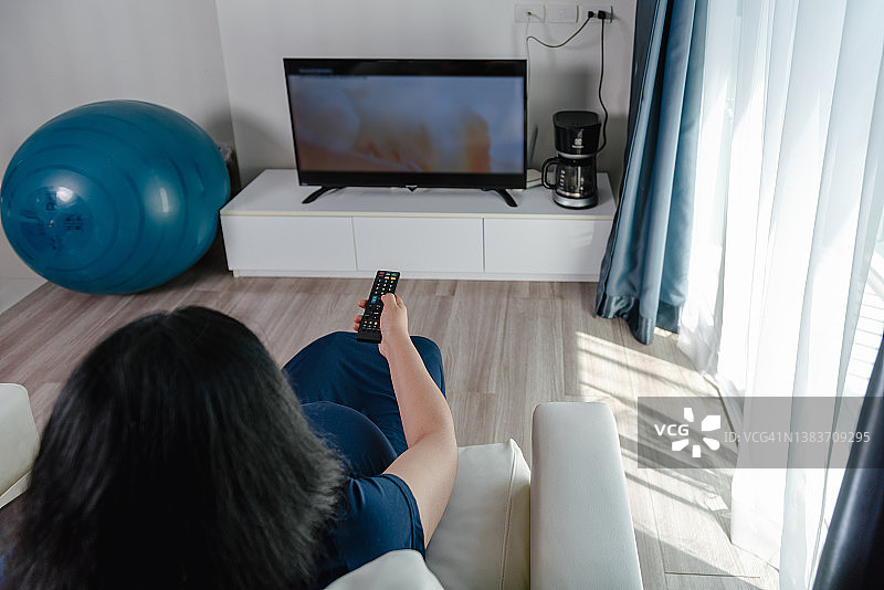 孕妇在客厅放松时用遥控器切换电视频道特写图片素材