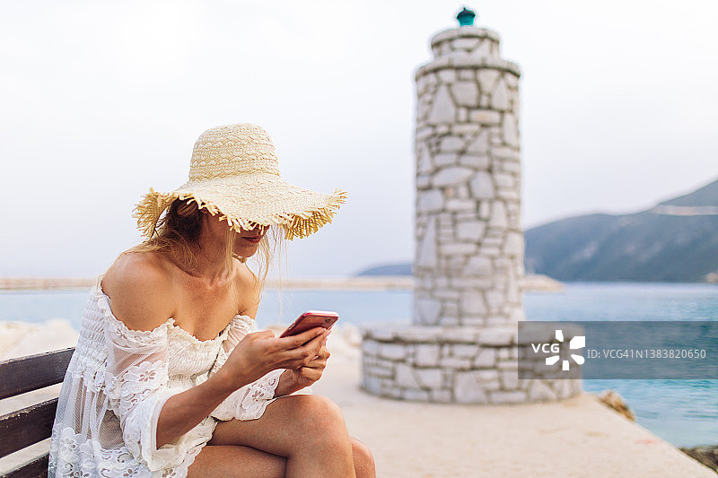 享受假期并使用手机的美丽女人图片素材