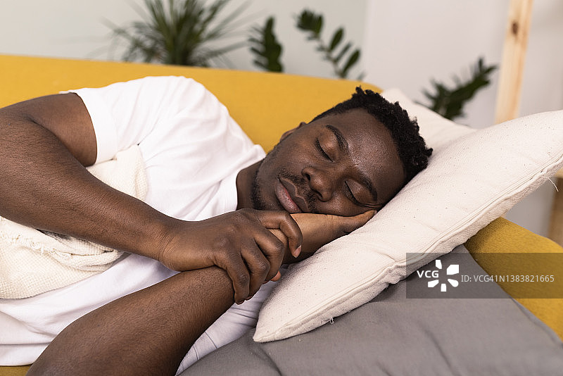 因喉咙痛而睡在沙发上的年轻非洲裔男子肖像图片素材