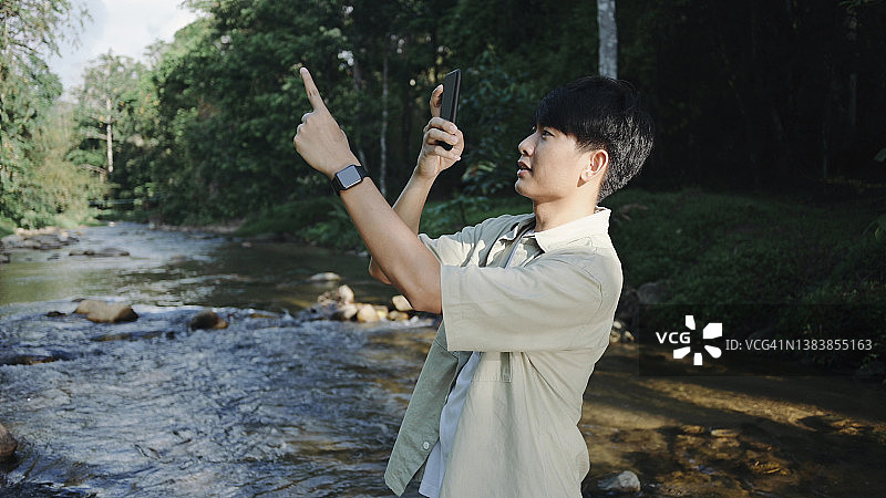 年轻的亚洲网红游客在森林里看数码设备录制视频图片素材