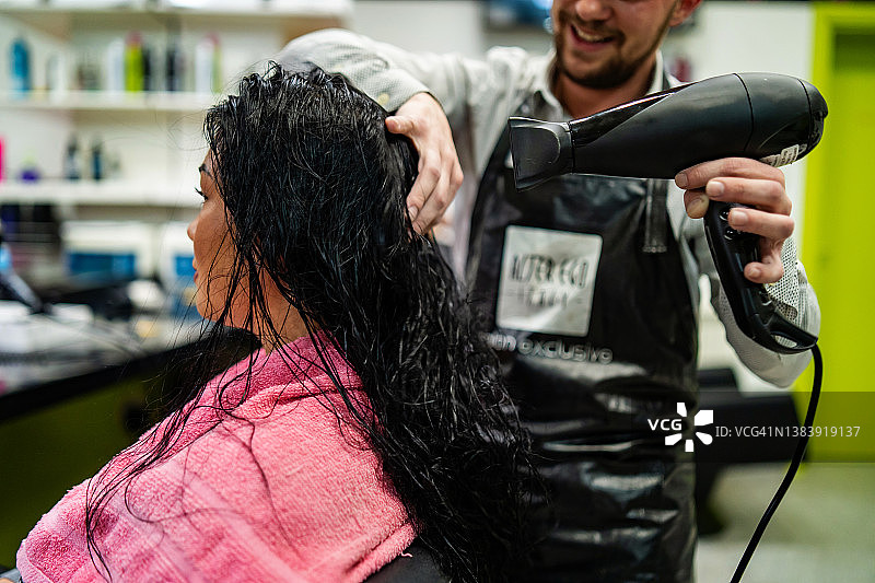 发型师用吹风机吹干湿的黑色头发图片素材