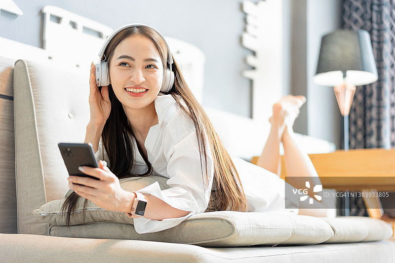 在客厅听音乐的亚洲年轻女子图片素材