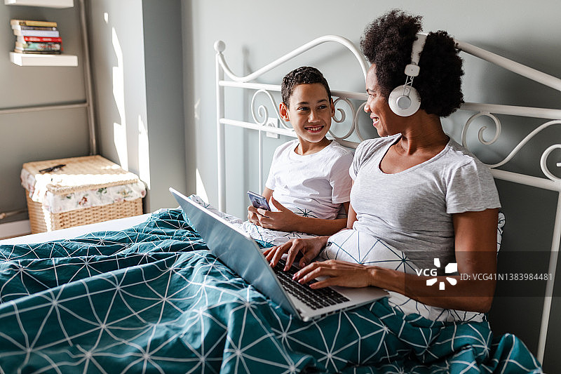母子在床上使用科技产品图片素材