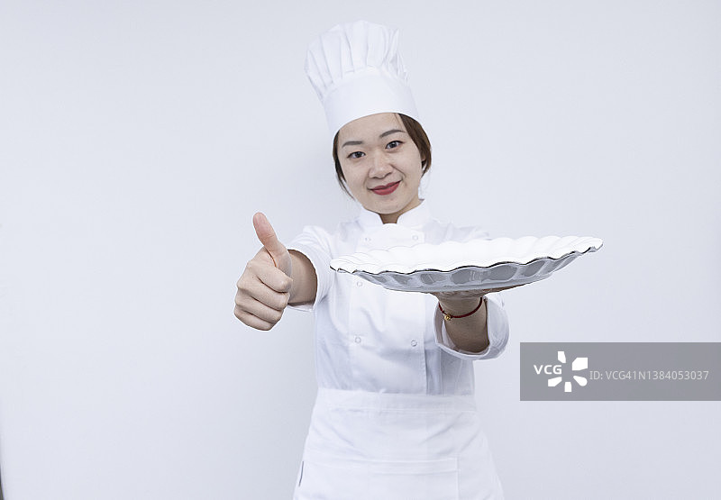 戴着厨师帽、手捧圆顶托盘和空盘子的亚洲女厨师宣传素材图片素材