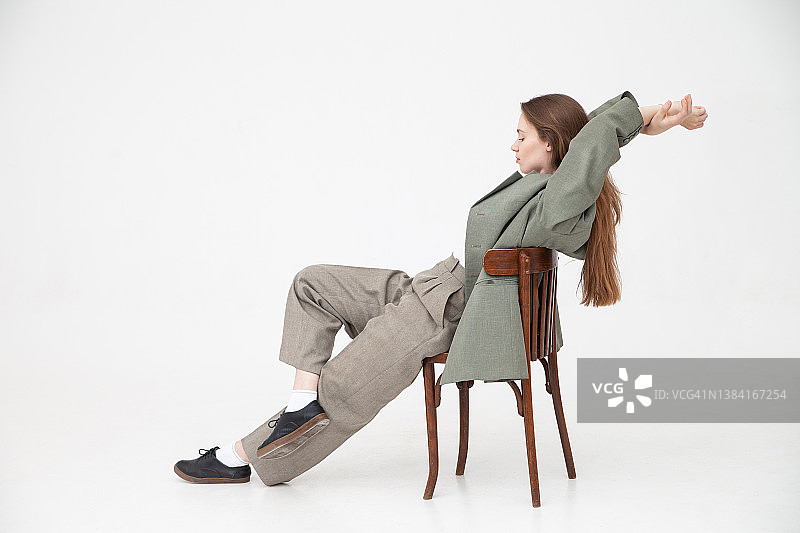 穿着宽松衣服坐在旧椅子上的沉思的女人图片素材