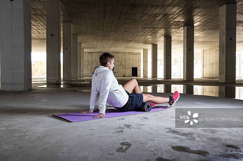 年轻男子在泡沫轴上伸展身体图片素材