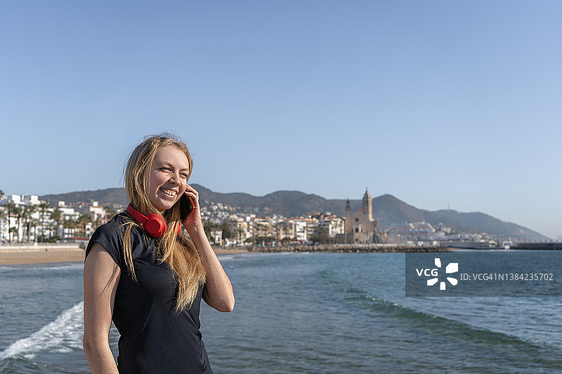 金发美女在海边乡村背景下用智能手机交谈的肖像图片素材