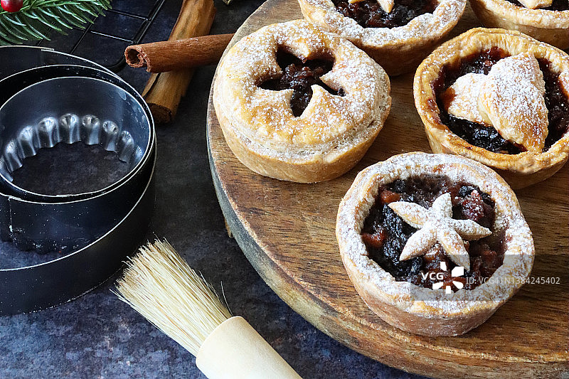 木制案板上的自制肉馅饼，饰有糕点星星，云杉针叶，红色浆果和肉桂棒图片素材