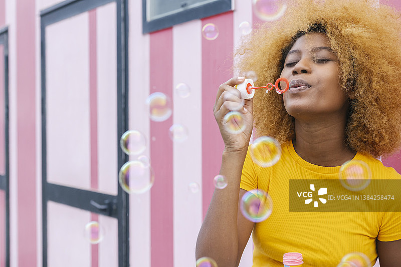 在户外吹肥皂泡，玩得很开心的年轻非洲裔女子图片素材