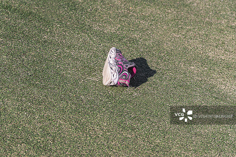 一双紫白色运动鞋，放置在人造草坪上图片素材