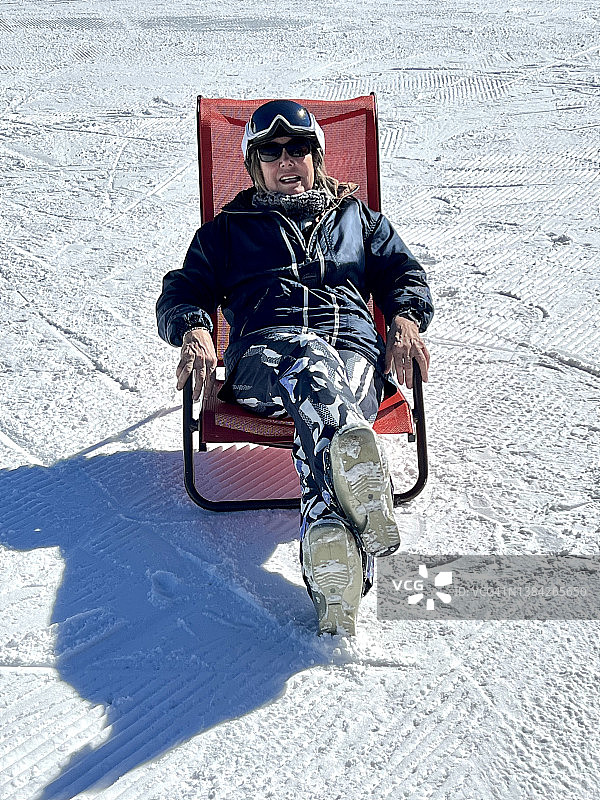 年长的女人在雪地里的躺椅上放松身心图片素材