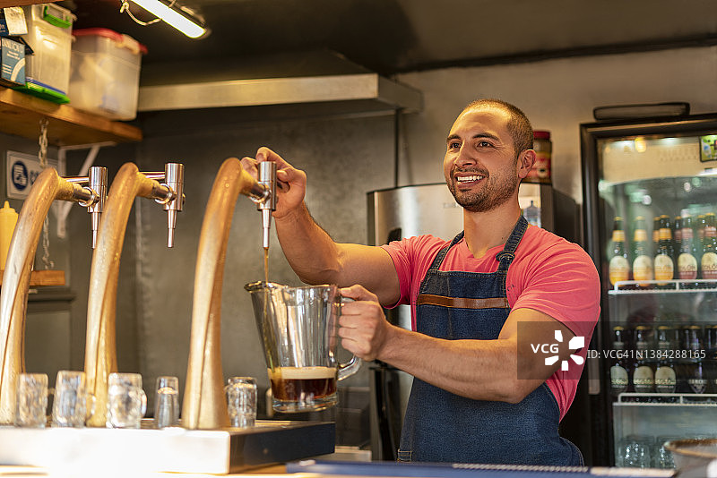 在小型饮料店工作的男人提供啤酒图片素材