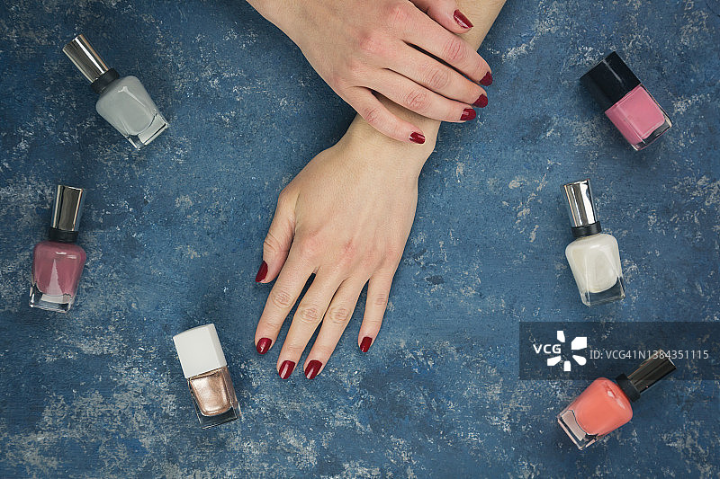 涂有指甲油的女人手，蓝色背景图片素材