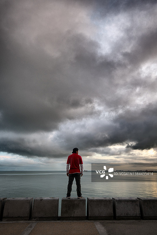 男人在阴沉的天空下看海的背影图片素材