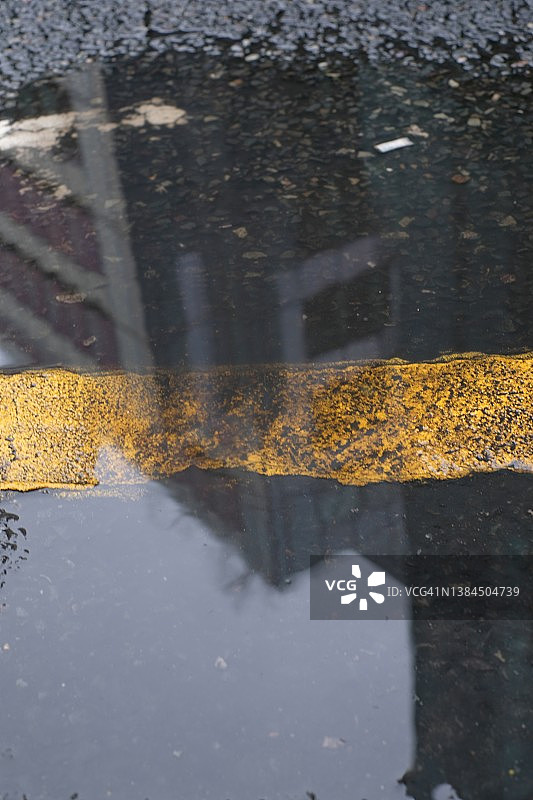 湿沥青路面上宫殿和摩天大楼的黄色条纹倒影图片素材