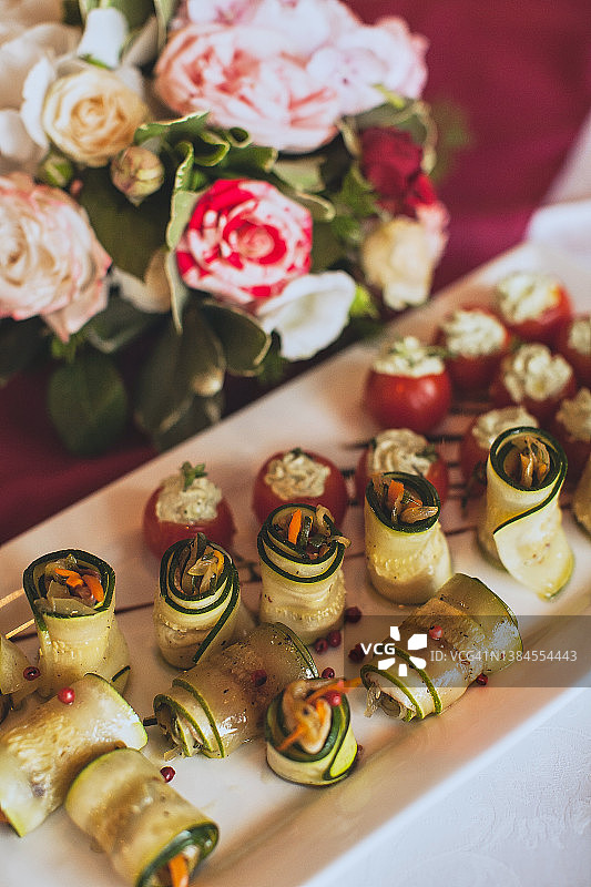 炸西葫芦卷，内馅是白软干酪和蔬菜，在白色盘子里，在家中、餐厅或咖啡馆。简单又美味的西葫芦食谱。素食和纯素食品的概念。素食主义和纯素主义的概念图片素材