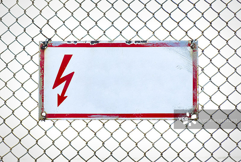金属丝网围栏上的危险警告标志：禁止入内，高压危险，红色闪电图片素材