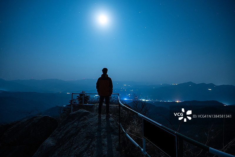 月夜下男人站在山顶仰望星空背影图片素材