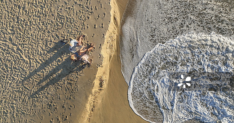 日出时一家人在海滩放松身心的鸟瞰图图片素材