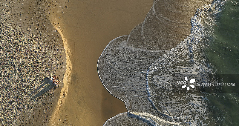 日出时一家人在海滩放松身心的鸟瞰图图片素材