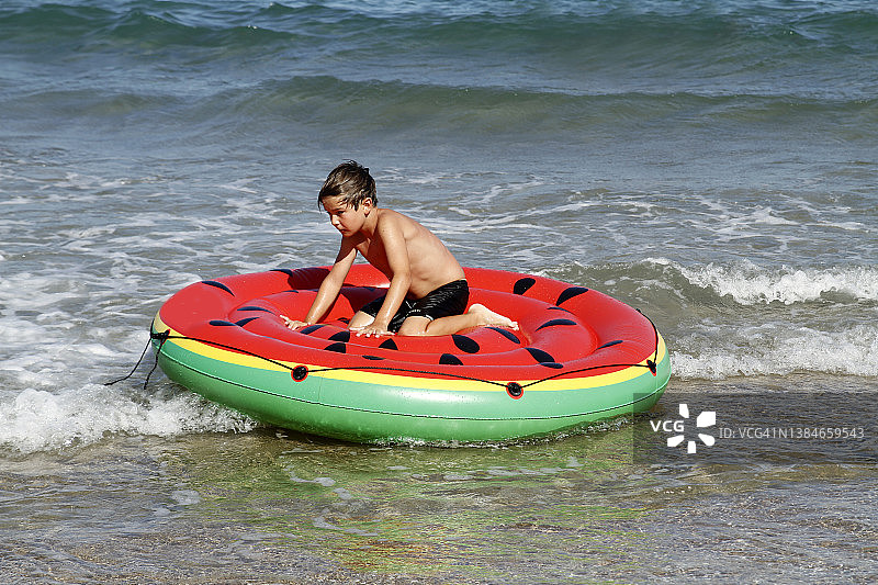 男孩在海上充气西瓜上放松图片素材